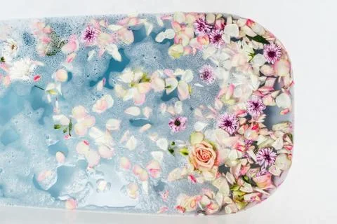 Top view of bath filled with blue bubble water, flowers and petals, spa or se Foto stock