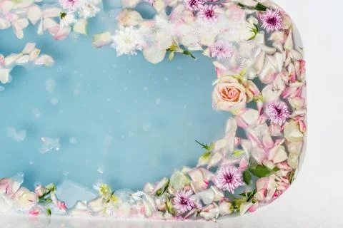 Top view of bath filled with blue bubble water, flowers and petals, spa or se Stock Photos