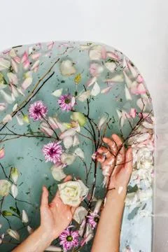 Top view of bath filled with blue bubble water, flowers, branches and petals  Stock Photos