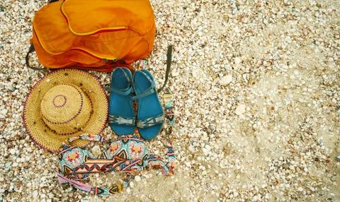 Top view beach accessories on seashells. Straw hat, orange bag, sandals and Stock Photos