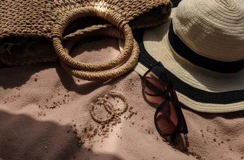 Top view of beach accessories: straw hat, summer bag, sunglasses and earrings Stock-Fotos
