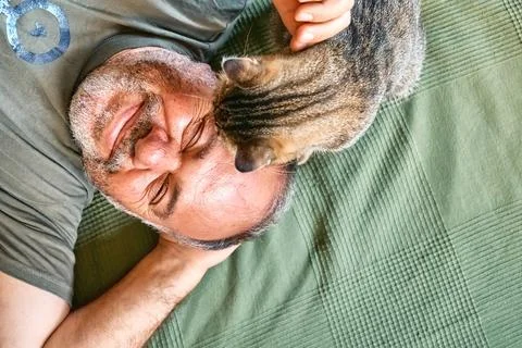 Top view of bearded middle-aged man lying on a bed and playing with his gra.. Stock Photos