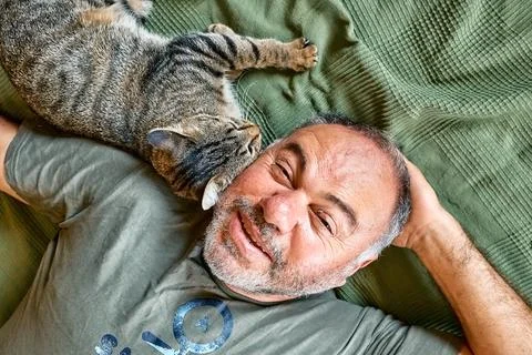 Top view of bearded middle-aged man lying on a bed and playing with his gra.. Stock Photos