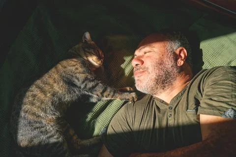 Top view of bearded middle-aged man lying on a bed and playing with his gra.. Stock Photos