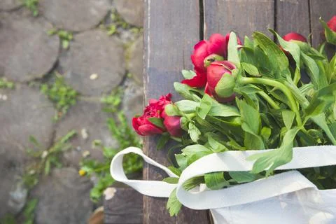 Top view on beautiful bunch of red peonies in textile bag on the wooden backg Stock Photos