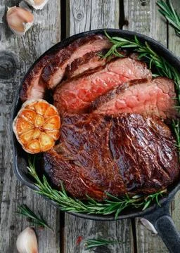 Top view of a beef steak medium rare with baked garlic and rosemary in a blac Foto stock