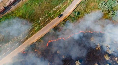 Top view at the beginning of the fire in a grassy field near the road Stock Photos