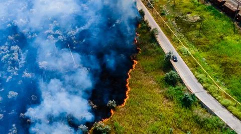 Top view at the beginning of the fire in a grassy field near the road Stock Photos