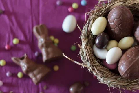 Top view of bird nest with easter eggs and sweets on table Stock Photos