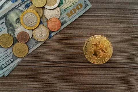Top view of a bitcoin lying next to a stack of dollars and coins on the table Stock Photos