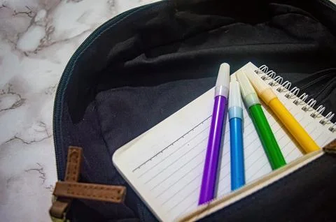 Top view of a black backpack with a notebook and four colorful markers insi.. 写真素材
