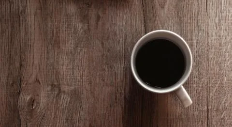 Top view of black coffee in white cup on wooden table. Brown tone photo Stock Photos