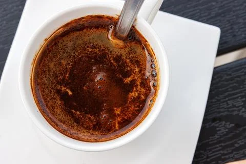 Top view of black coffee in a white cup with spoon and saucer on a dark woo.. Stock Photos