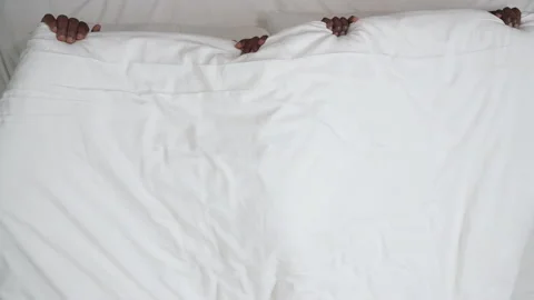 Top view of black couple covered under blanket, throwing it off abruptly and Stock Footage 136508436