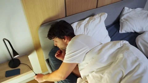 Top view of a black-haired man who uses a smartphone late at night, turns off 스톡 동영상 233283387