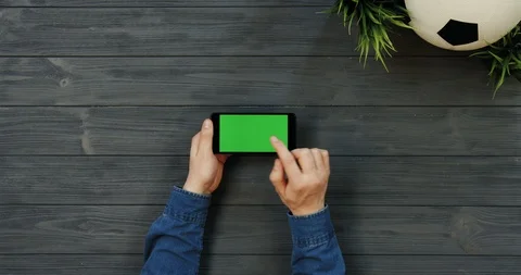 Top view on the black horizontal smartphone with green screen in hands of man Stock Footage 96308373