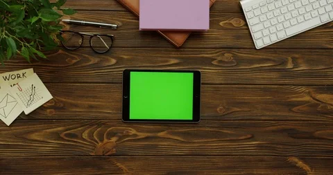 Top view on the black horizontal tablet device with a green screen on the wooden Stock Footage 88378561