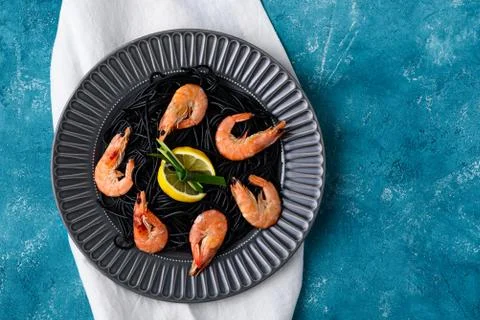 Top view black paste with cuttlefish ink with shrimps and lemon slices in gre Stock Photos
