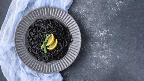 Top view black paste with ink cuttlefish and lemon slices in gray plate on gr Stock Photos