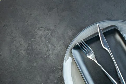 Top view black plate with fork knife and gray plate on dark background silv.. Stock Photos