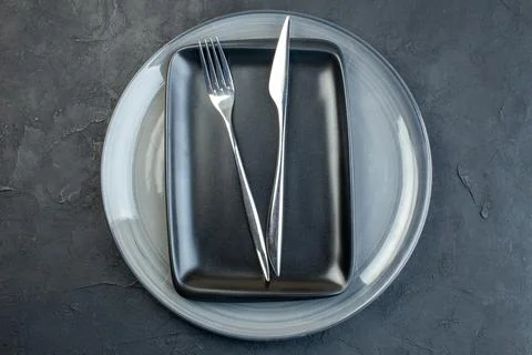 Top view black plate with fork knife and gray plate on dark background silv.. Stock Photos