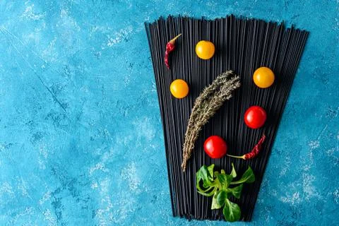 Top view black spaghetti with cuttlefish ink on blue background with yellow a Stock Photos