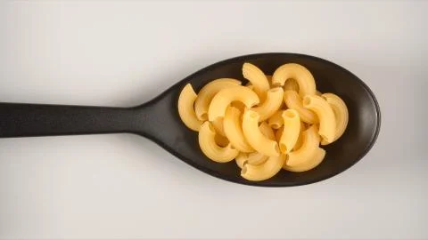 TOP VIEW: Black spoon with figural pasta Stock Photos