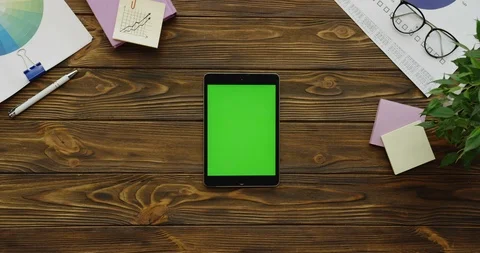 Top view on the black tablet computer with a green screen lying vertically on Video stock 88389107