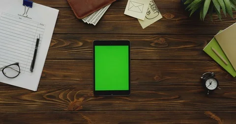 Top view on the black tablet device with a green screen lying vertically on the 스톡 동영상 88402285