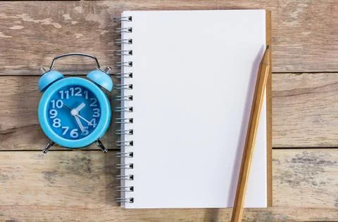 Top view with blank empty notepad, alarm clock and pencil on wood table. Foto stock