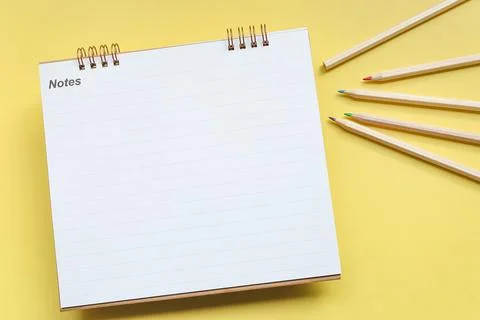 Top view of blank lined notebook and colored pencil on yellow background. Stock Photos