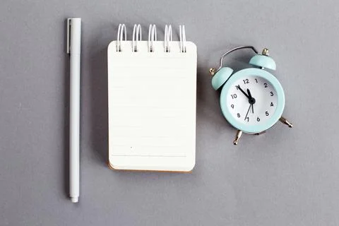 Top view of blank note paper with pen and alarm clock on gray background 스톡 사진