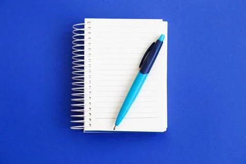Top view of blank note paper with pen on blue background Foto stock