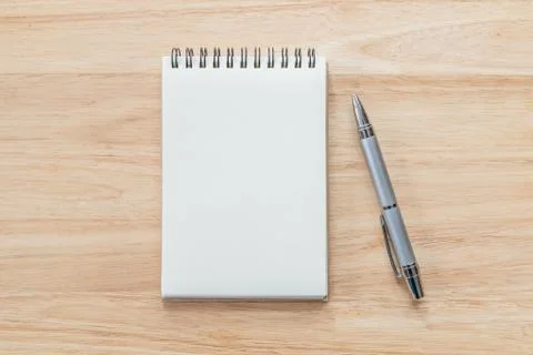 Top view of blank notebook with pen and natural light on wooden table. Stock Photos