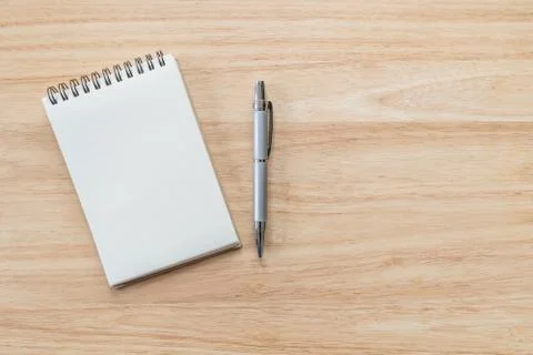 Top view of blank notebook with pen and natural light on wooden table. Stock Photos