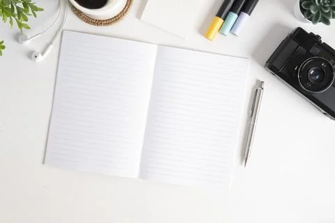 Top view blank notepad, camera, coffee cup and stationery on white table. Stock Photos