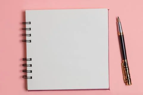 Top view of a blank notepad next to a pen on a pink background. Stock Photos