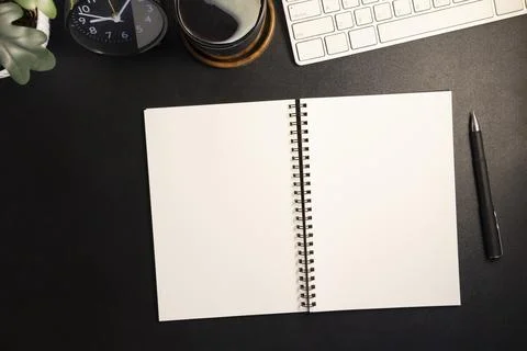 Top view blank notepad, pen, coffee cup and keyboard on black wooden table. Foto stock