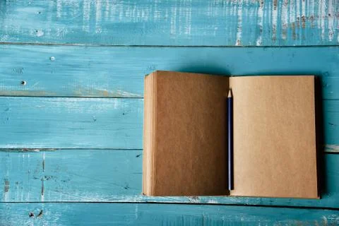 Top view of blank open notebook on blue wooden background with purple pencil  Photos