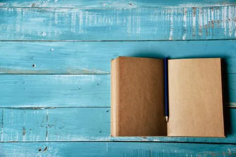 Top view of blank open notebook on blue wooden background with purple pencil  Fotos de archivo