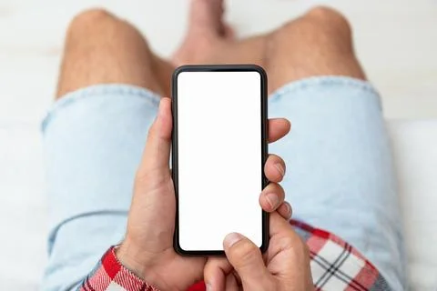 Top view of blank screen of smart phone in male hands. Stock Photos