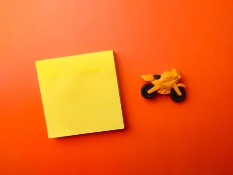 Top view blank sticky note with toy motorbike on a orange background Stock Photos