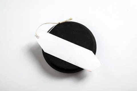Top view of a blank white paper tag with a string placed on a round black s.. Stock Photos