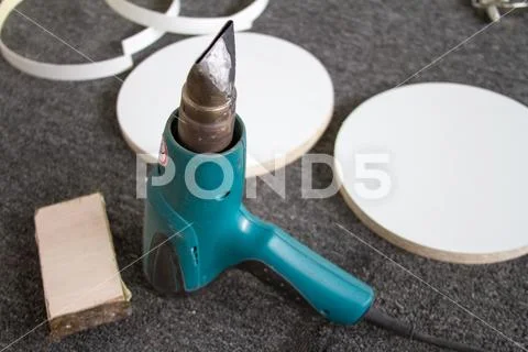 Top view of a blue construction heat gun on a gray background and furniture d Stock Photos