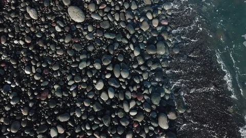Top view on blue ocean waves with white foam cover stones at the shore in sunny Stock Footage 95714645