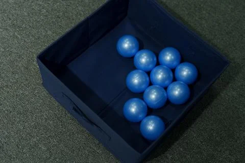 Top view of blue plastic balls collected inside a dark blue storage box Stock Photos
