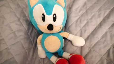 Top view of a Blue Sonic The Hedgehog toy plush on a bedsheet Stock Footage 241398922