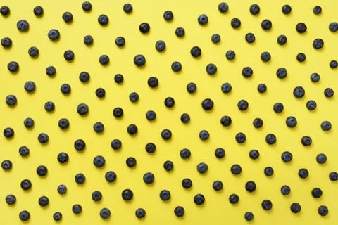 Top view of blueberries pattern on yellow background. Summer food concept Stock Photos