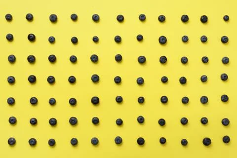 Top view of blueberries pattern on yellow background. Summer food concept Stock Photos
