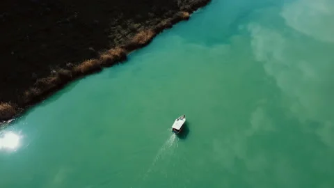 Top view of a boat sailing on the river. Reflection of sky and sun on the river. Stock Footage 236955241
